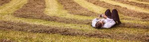 contact us -man lying in a field on his phone - hoseco
